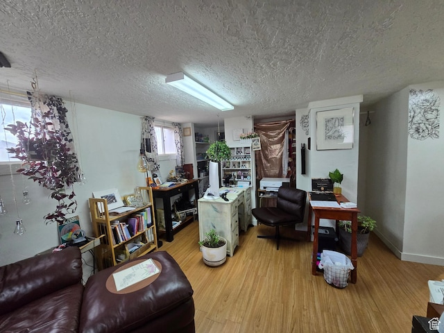 living area with a textured ceiling, light wood finished floors, and baseboards