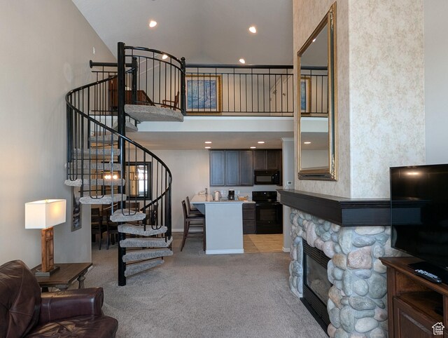 living room featuring a stone fireplace, a towering ceiling, and light carpet
