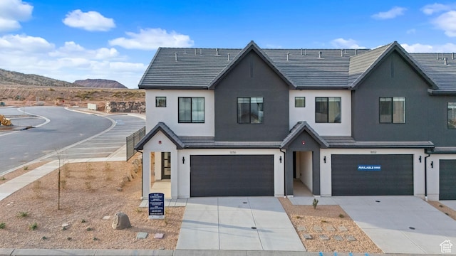 modern inspired farmhouse featuring concrete driveway, a mountain view, a garage, and stucco siding