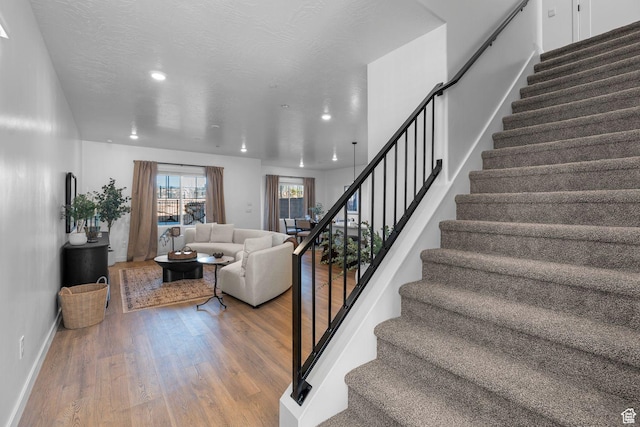 stairway with wood finished floors, baseboards, and recessed lighting
