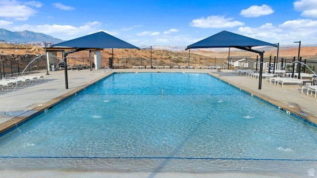 pool with a mountain view, fence, and a patio