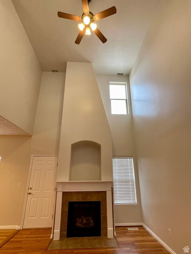 909 E Rosebud Ct, Draper, UT 84020 - unfurnished living room featuring hardwood / wood-style floors, a tile fireplace, ceiling fan, and a high ceiling