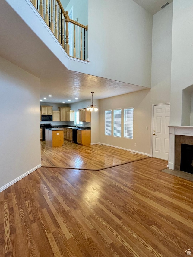 909 E Rosebud Ct, Draper, UT 84020 - unfurnished living room with hardwood / wood-style flooring, a high ceiling, an inviting chandelier, and a fireplace