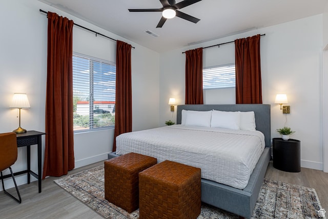 bedroom with light wood-type flooring, baseboards, a ceiling fan, and visible vents