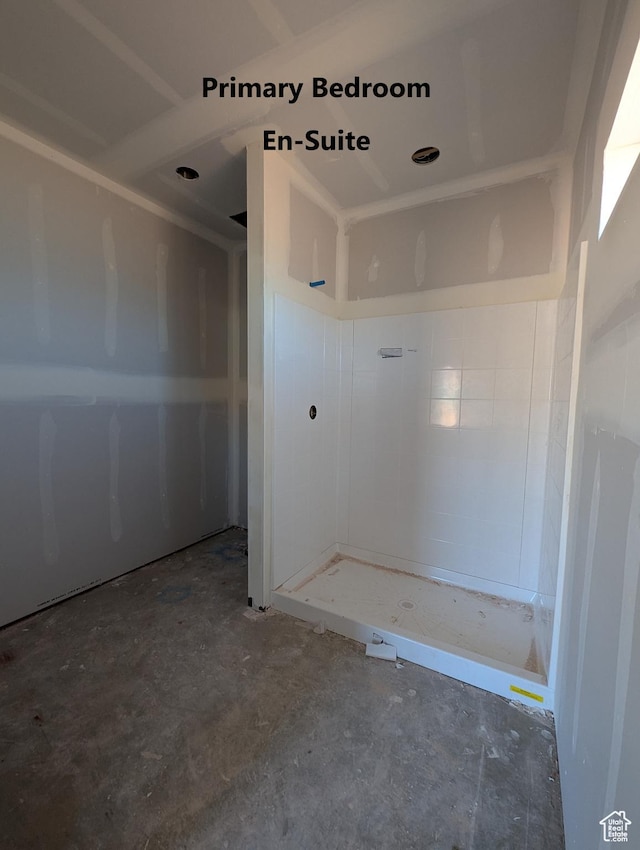 bathroom with concrete flooring and a tile shower