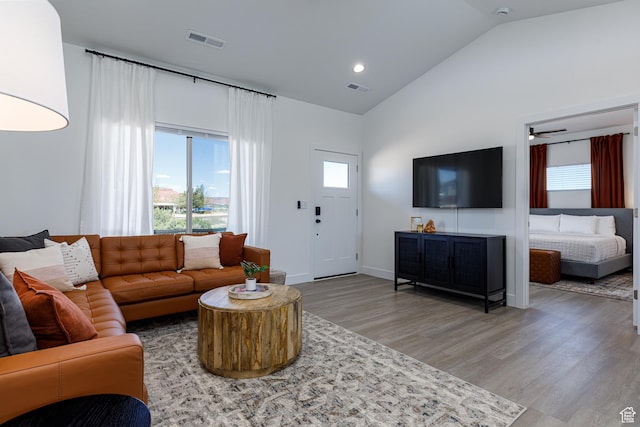 living room with baseboards, visible vents, high vaulted ceiling, and light wood-style floors