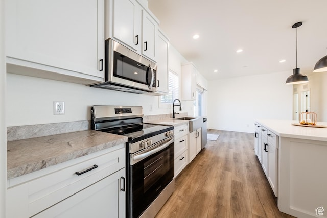 484 W Pipe Springs Dr, Kanab, UT 84741 - kitchen featuring sink, light hardwood / wood-style flooring, appliances with stainless steel finishes, white cabinets, and decorative light fixtures