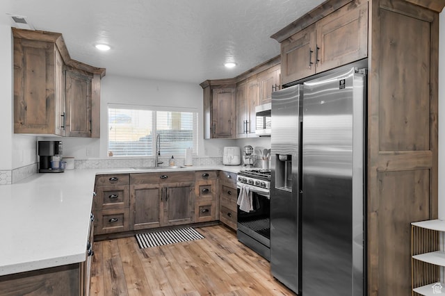 1426 S 1450 W, Mapleton, UT 84664 - kitchen with a textured ceiling, stainless steel appliances, a sink, visible vents, and light wood-style floors