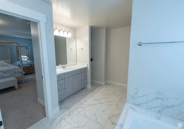 ensuite bathroom featuring marble finish floors, vanity, a bath, and baseboards
