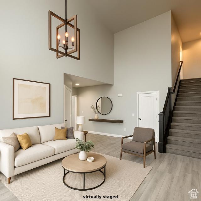 545 E Petersen Pkwy, South Weber, UT 84405 - living area with a towering ceiling, stairway, light wood-style floors, a chandelier, and baseboards