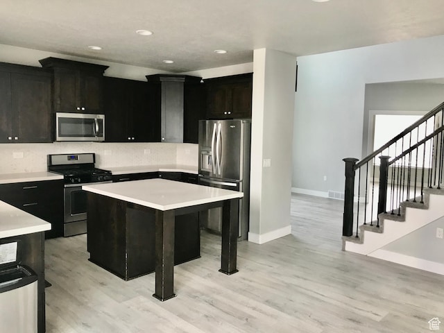 545 E Petersen Pkwy, South Weber, UT 84405 - kitchen featuring light wood finished floors, a kitchen island, stainless steel appliances, light countertops, and backsplash