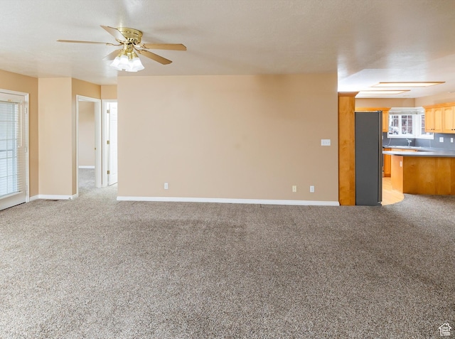unfurnished living room with light carpet and ceiling fan