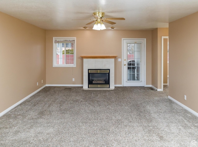 unfurnished living room with ceiling fan, a fireplace, and carpet