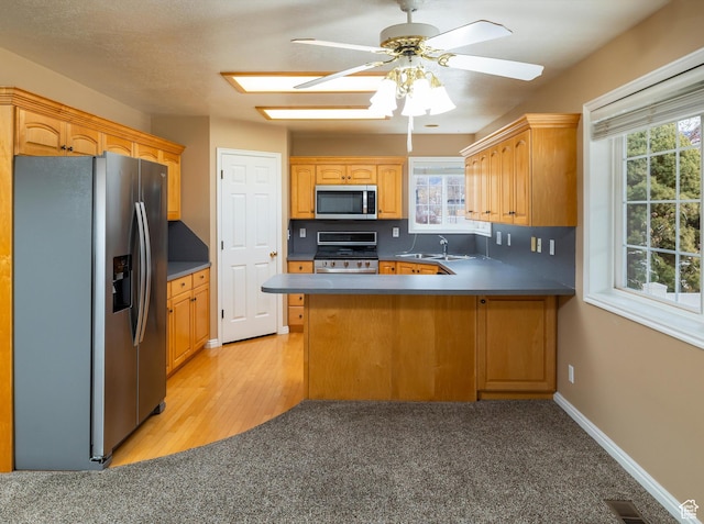 kitchen featuring sink, kitchen peninsula, ceiling fan, and appliances with stainless steel finishes
