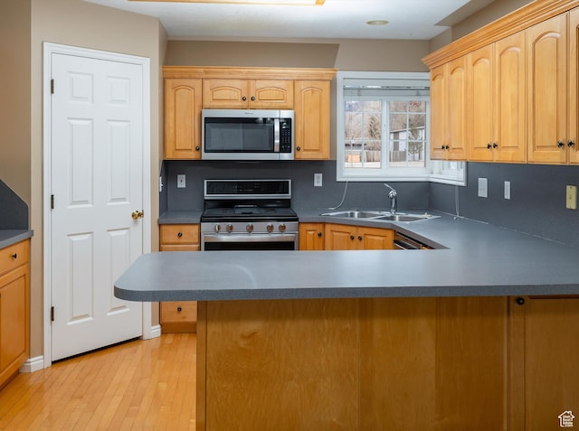 kitchen featuring appliances with stainless steel finishes, sink, light brown cabinetry, and light hardwood / wood-style flooring