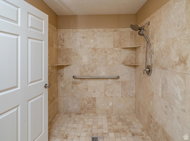 bathroom featuring a textured ceiling and a tile shower