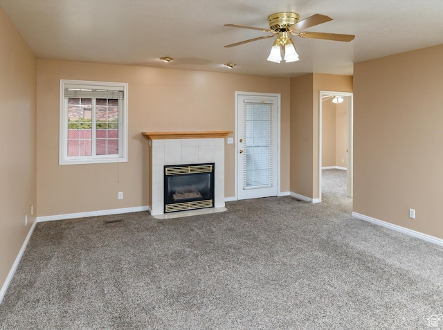 unfurnished living room featuring a tile fireplace, carpet, and ceiling fan