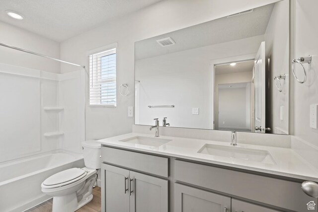full bath featuring toilet, wood finished floors, double vanity, recessed lighting, and shower / bath combination