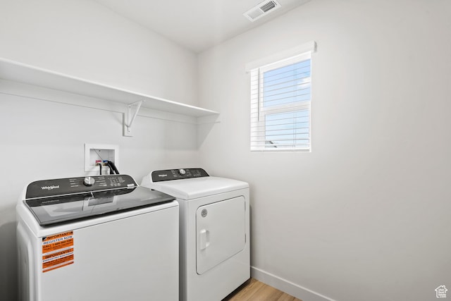 laundry room featuring independent washer and dryer, light wood finished floors, and baseboards