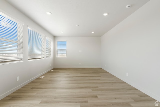 unfurnished room with a smoke detector, recessed lighting, light wood finished floors, and baseboards