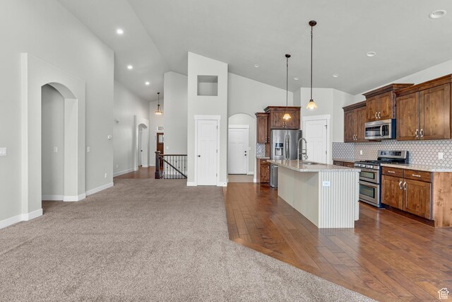 10743 S Autumn Wind Way S, Jordan, UT 84009 - kitchen featuring high vaulted ceiling, stainless steel appliances, tasteful backsplash, a center island with sink, and decorative light fixtures
