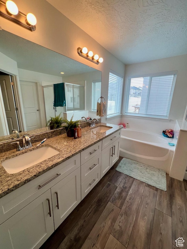 3457 W Hamm Ln, Herriman, UT 84096 - bathroom with a textured ceiling, wood finished floors, a bath, double vanity, and a shower stall