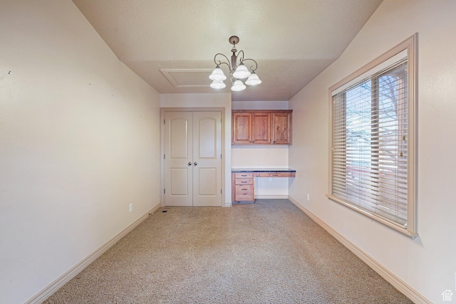 unfurnished dining area with an inviting chandelier, built in desk, and carpet floors