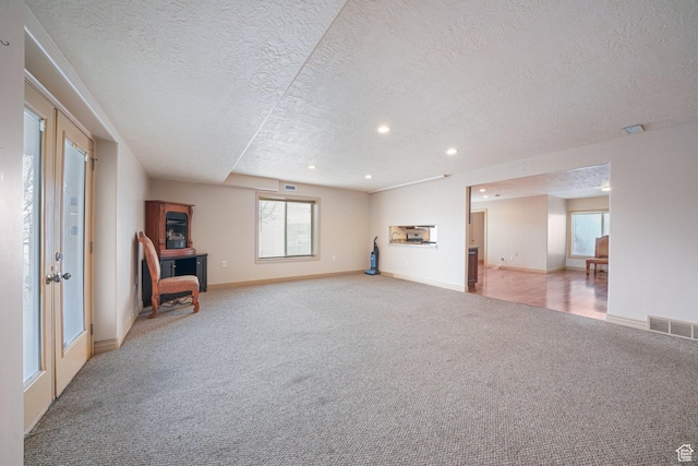 interior space featuring light colored carpet and a textured ceiling
