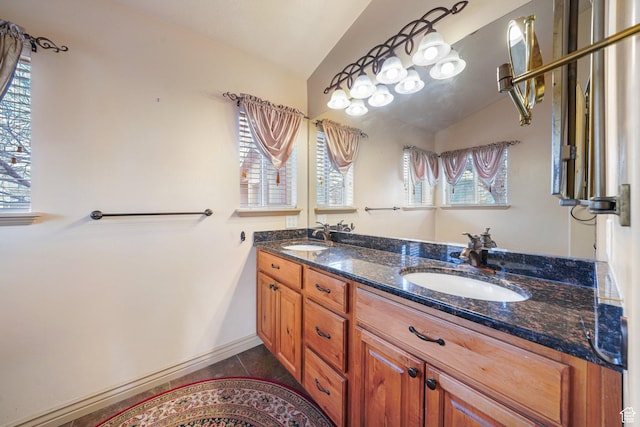 bathroom with tile patterned flooring, vaulted ceiling, and vanity
