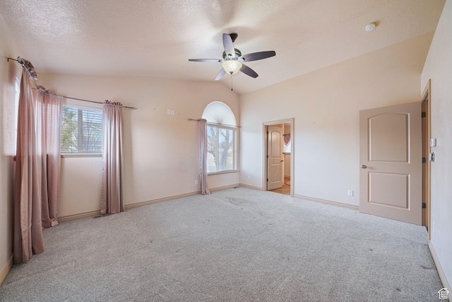 unfurnished bedroom with lofted ceiling, ensuite bath, light colored carpet, a textured ceiling, and ceiling fan