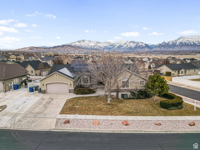 view of front facade featuring a garage, a mountain view, a front yard, and solar panels