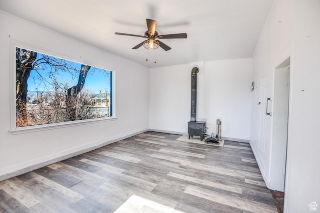 interior space featuring ceiling fan, a wood stove, and light hardwood / wood-style floors