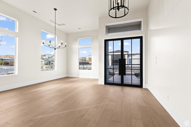 interior space featuring light hardwood / wood-style flooring, french doors, and a chandelier