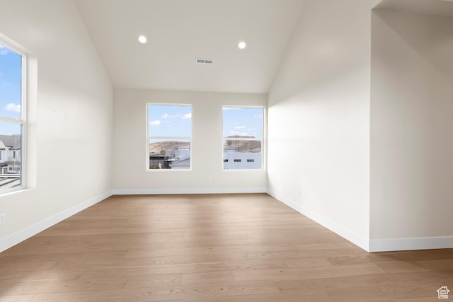 empty room featuring vaulted ceiling and light wood-type flooring