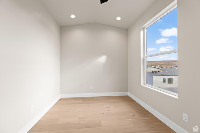spare room featuring vaulted ceiling and light hardwood / wood-style floors