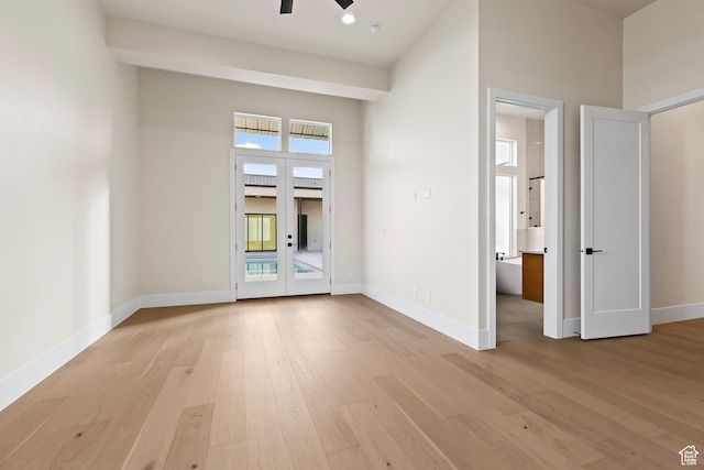 unfurnished room featuring a towering ceiling, light hardwood / wood-style floors, french doors, and ceiling fan