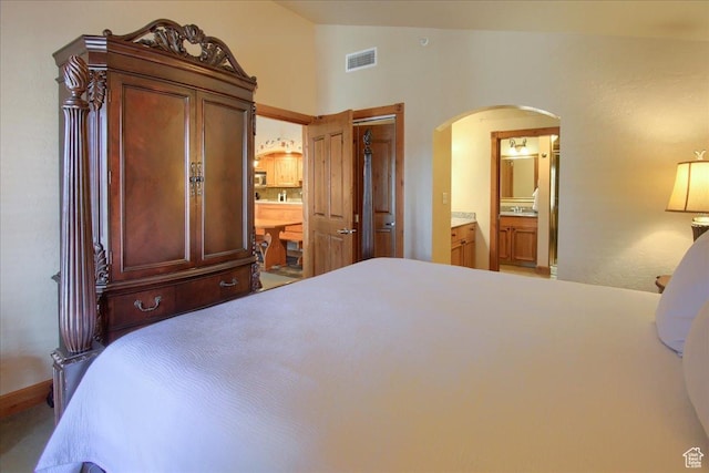 bedroom with connected bathroom and vaulted ceiling