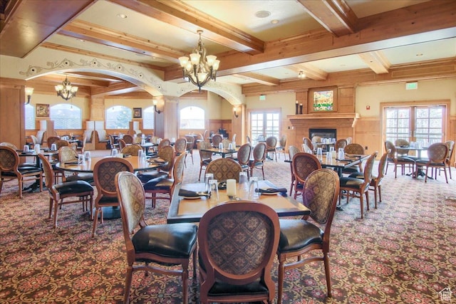 dining area featuring beamed ceiling, carpet floors, a fireplace, and a chandelier