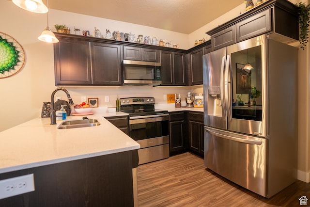 14497 S Ronan Ln E Unit O-002, Herriman, UT 84096 - kitchen with sink, hanging light fixtures, dark brown cabinetry, light hardwood / wood-style floors, and stainless steel appliances