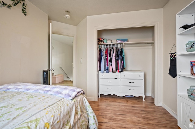 bedroom with a closet, wood finished floors, and baseboards