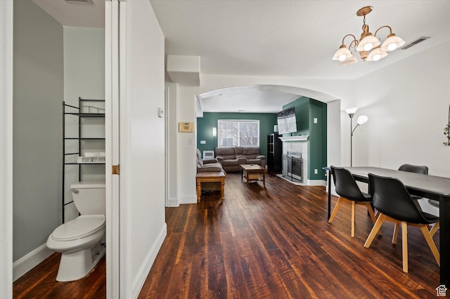 interior space featuring baseboards, visible vents, toilet, wood finished floors, and a fireplace