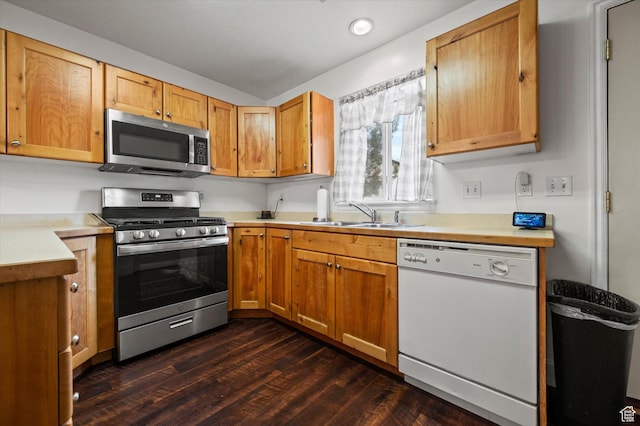 kitchen with stainless steel appliances, light countertops, a sink, and dark wood finished floors