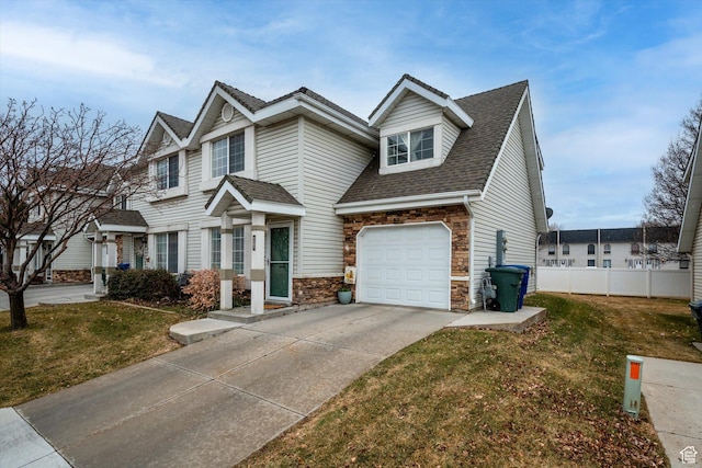 view of front of property with stone siding, a front lawn, concrete driveway, and a shingled roof