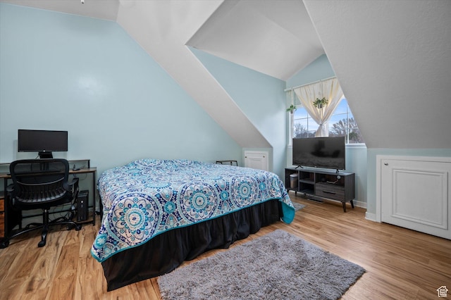 bedroom featuring baseboards, vaulted ceiling, and wood finished floors
