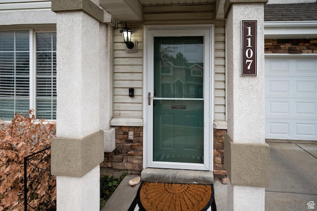 property entrance featuring stone siding, roof with shingles, and stucco siding