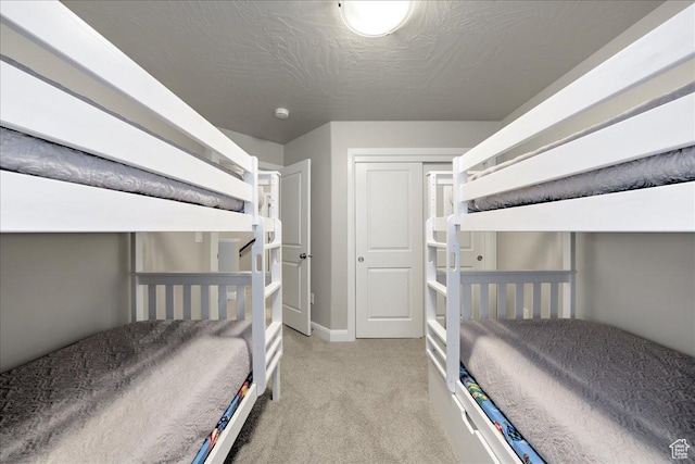 bedroom featuring light colored carpet and a textured ceiling