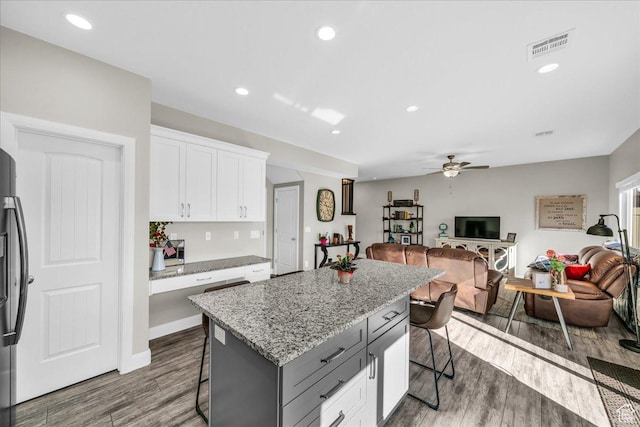 kitchen featuring gray cabinetry, white cabinets, a kitchen bar, a center island, and light stone countertops