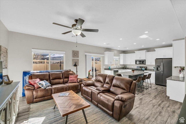 living room featuring ceiling fan, sink, and light hardwood / wood-style floors