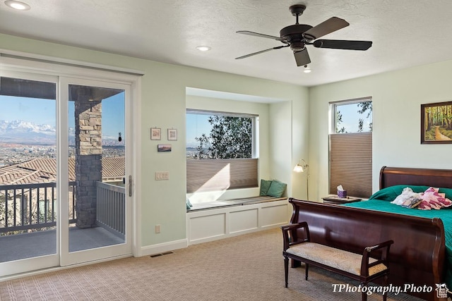 carpeted bedroom featuring ceiling fan, access to exterior, and a textured ceiling
