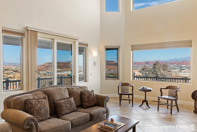living room with plenty of natural light, a mountain view, a high ceiling, and light tile patterned floors